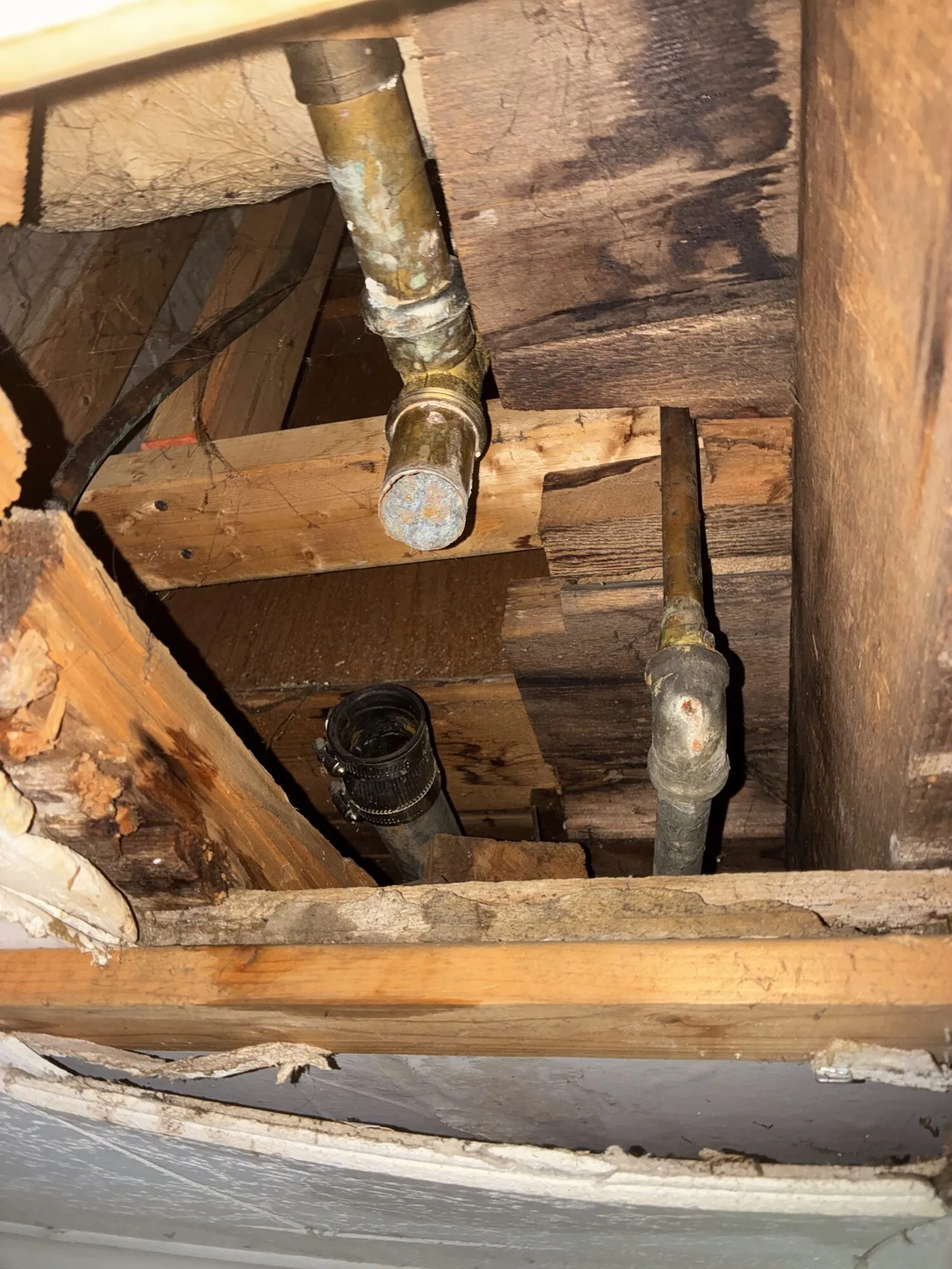 Opened joist bay with corroded pipe and a new coupling