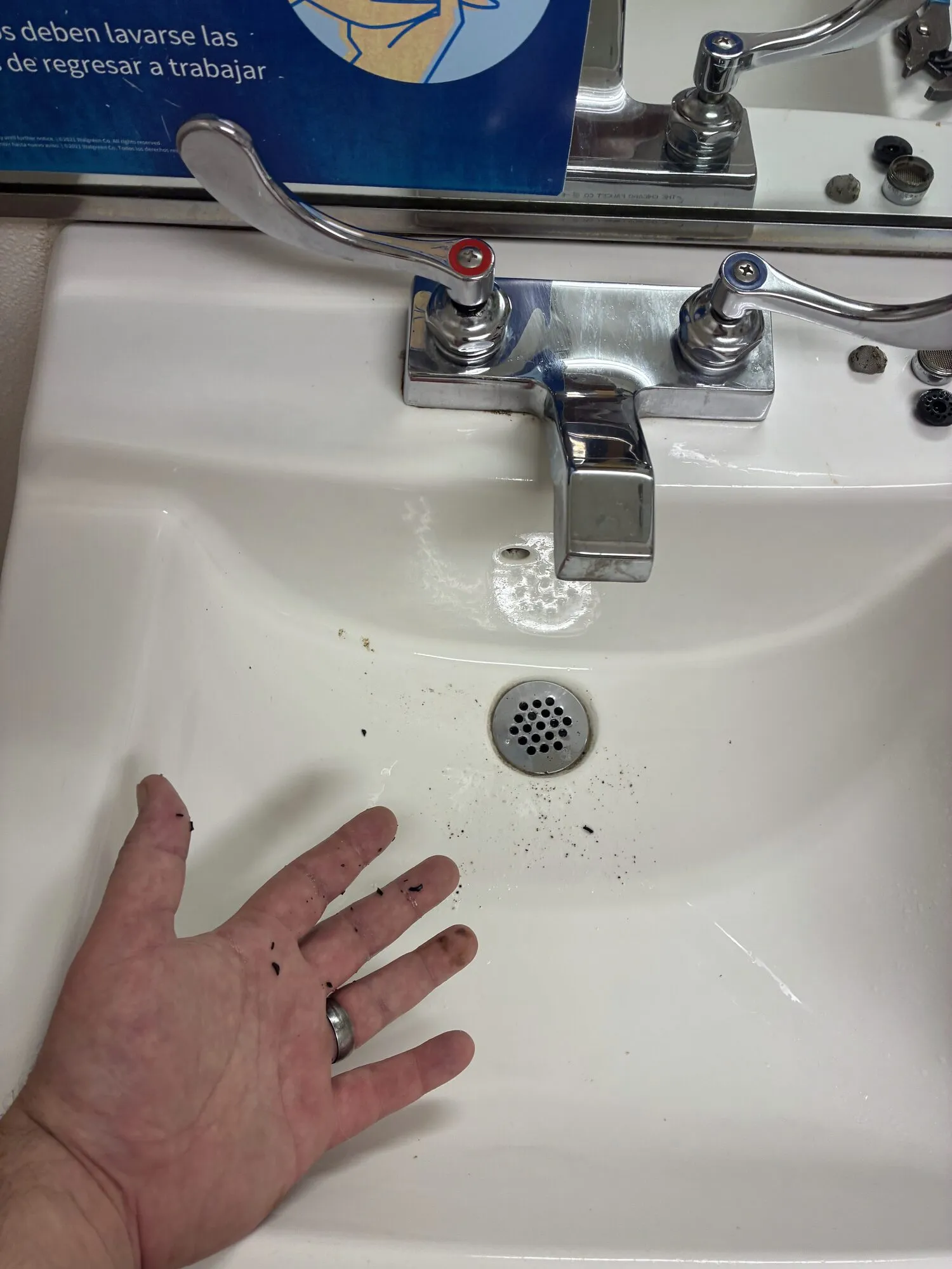 A commercial restroom sink with grit around the strainer