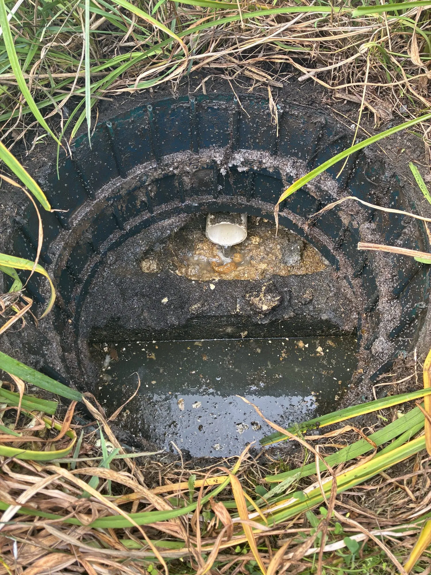 An opened septic tank lid showing the inlet baffle