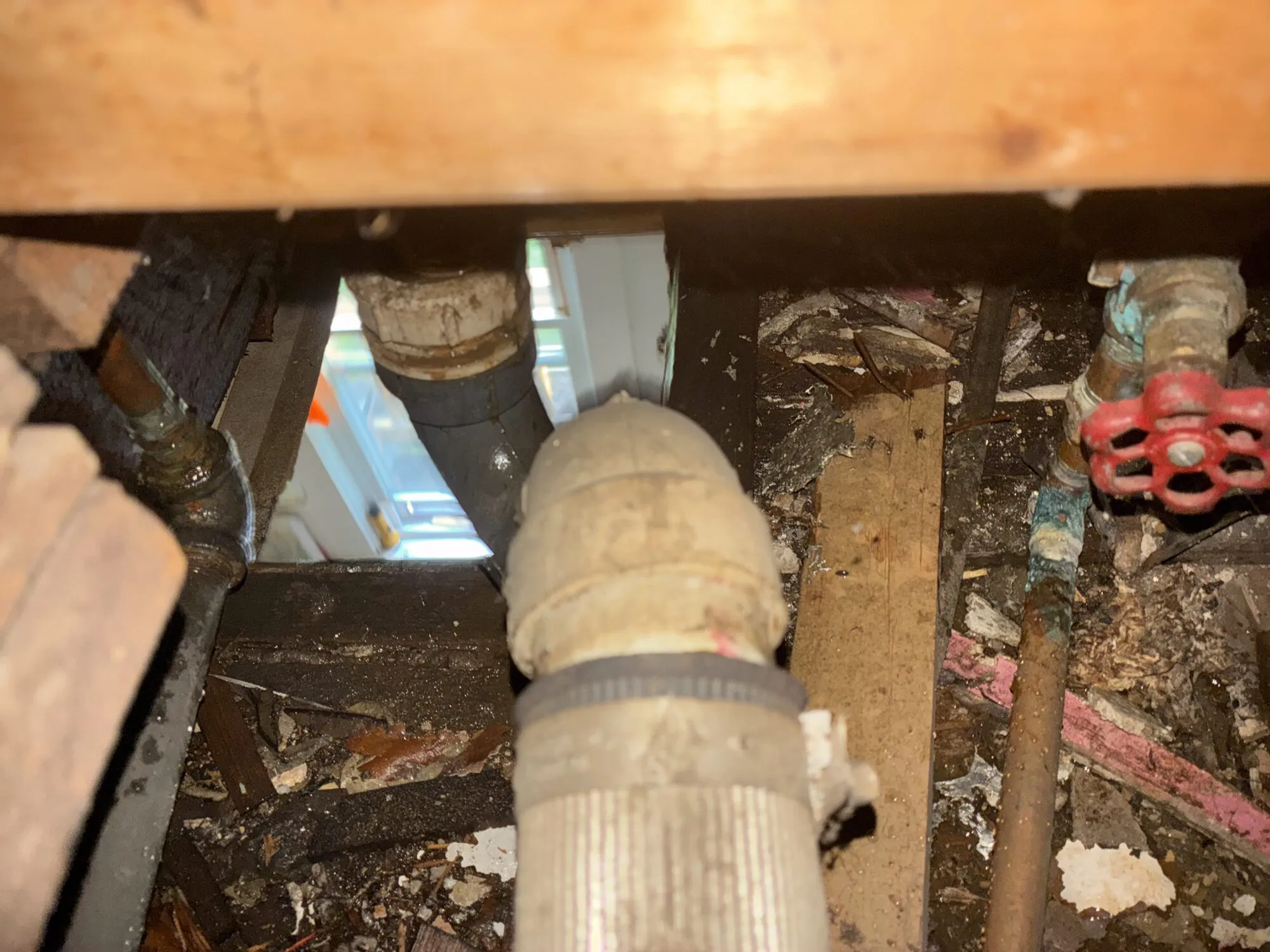 Old cast iron and copper waste lines opened up under a floor